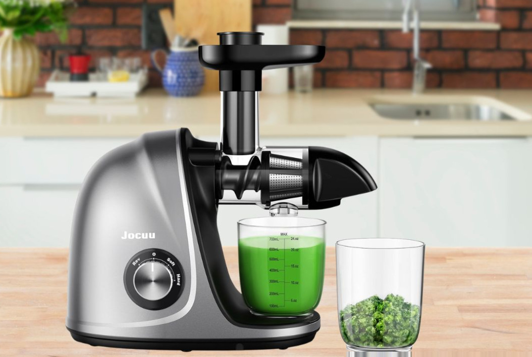 Jocuu Slow Masticating Juicer in teal with clear juice glass and dry pulp container on white marble